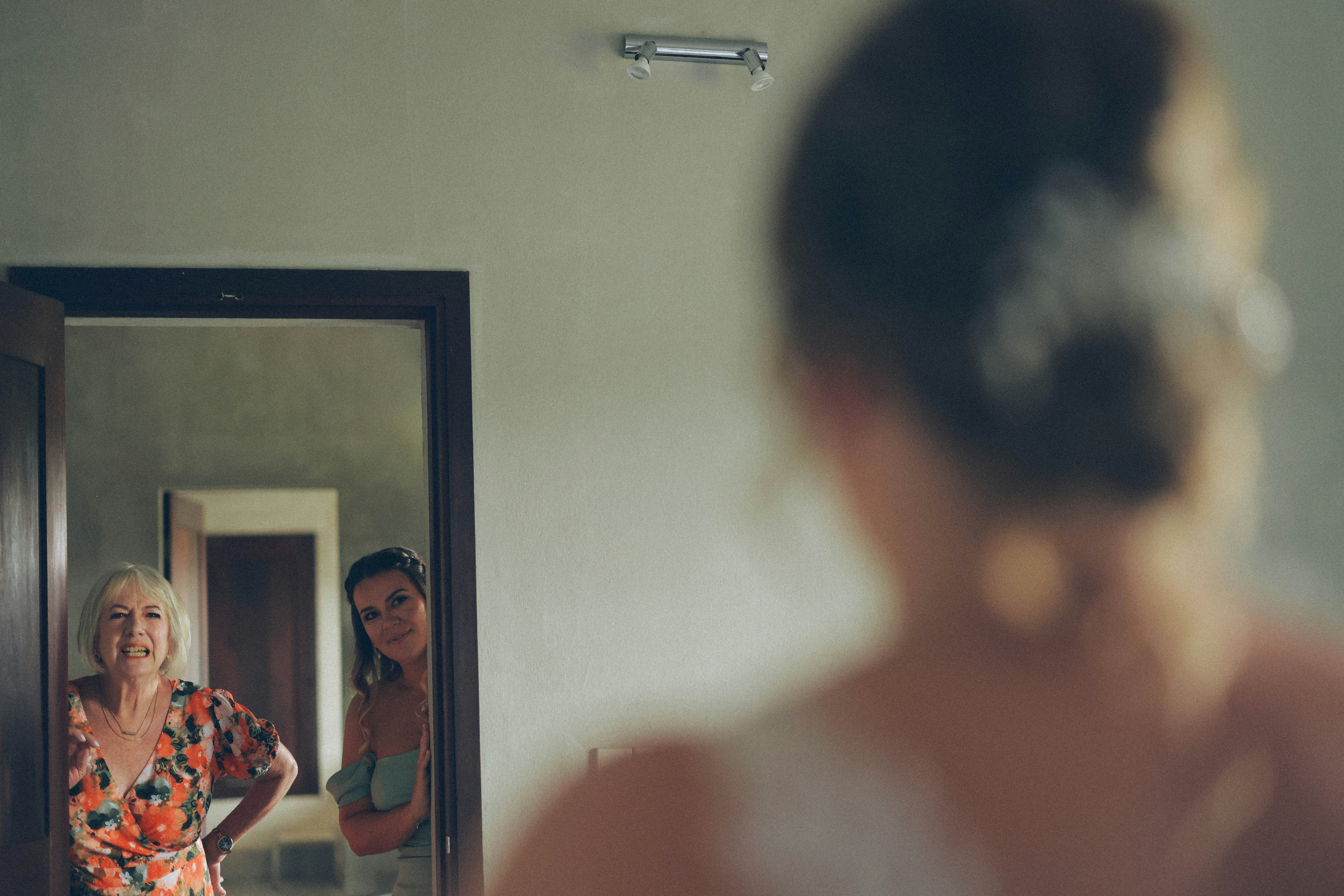 Two women reflected in a mirror looking at bride