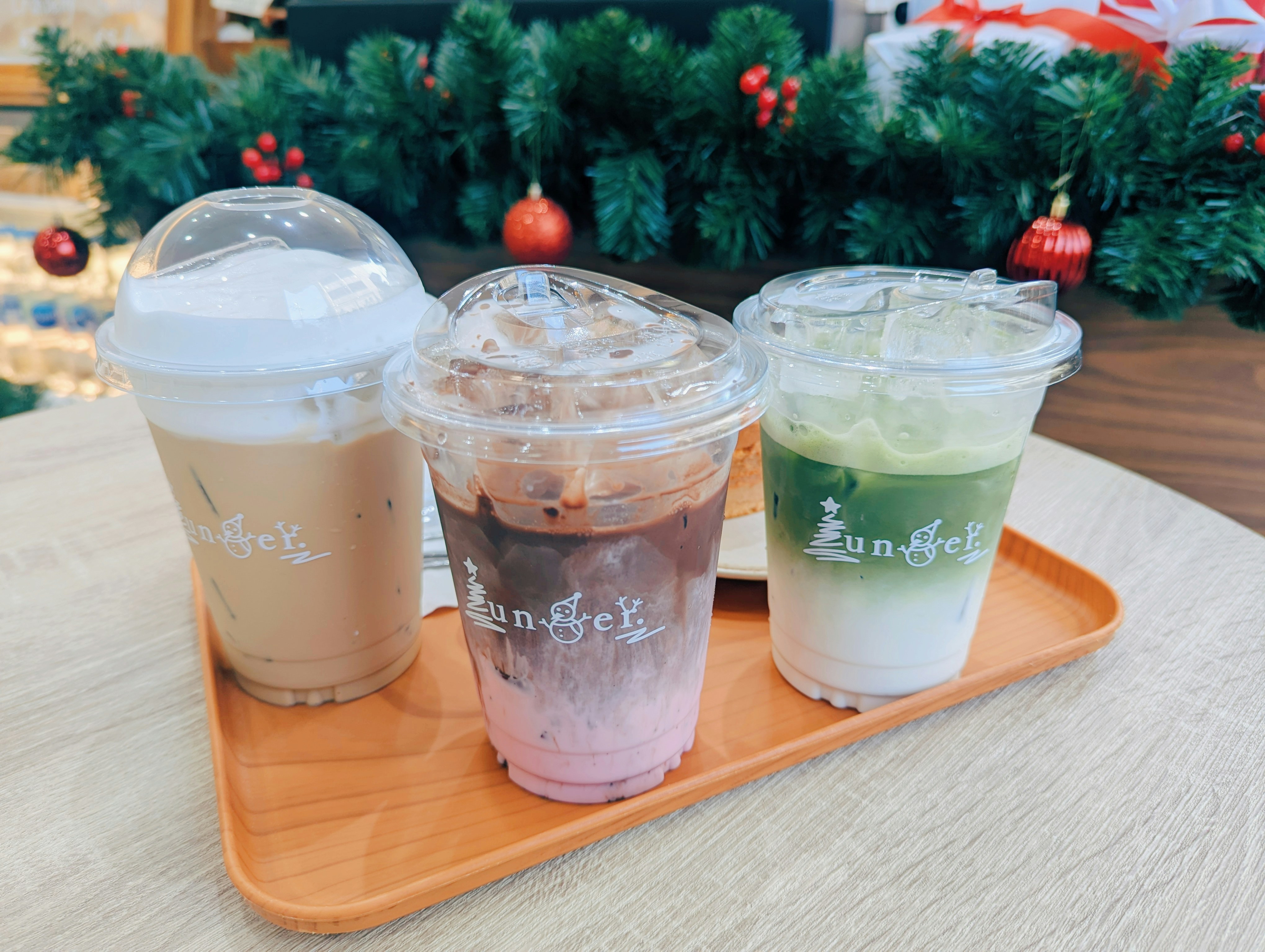 Three iced coffees on a tray with christmas decor.