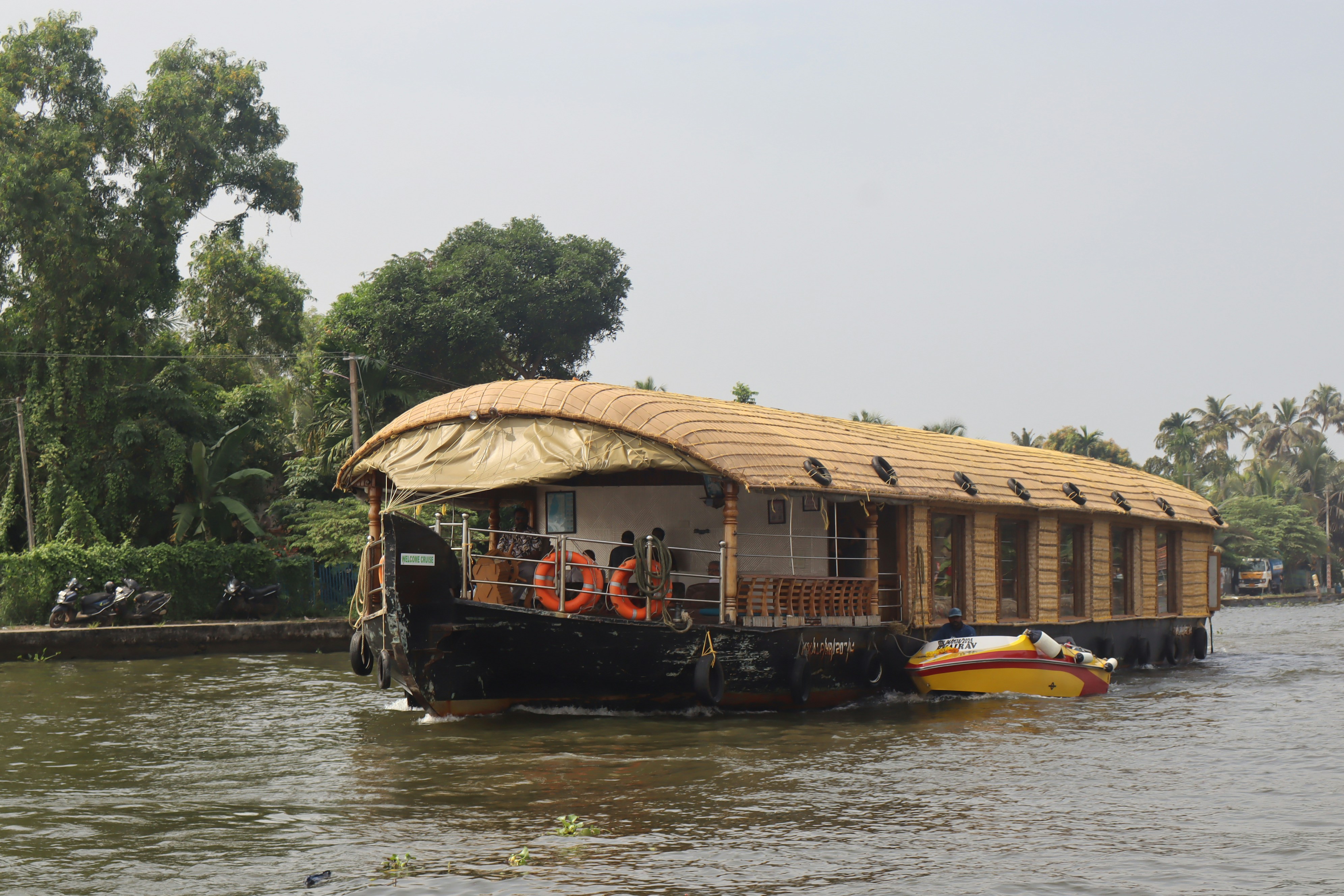 A houseboat with a thatched roof on a river.