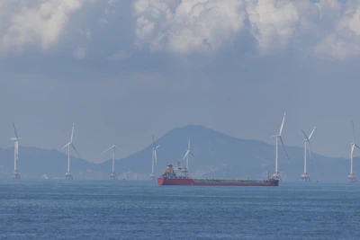 Cargo ship sailing past offshore wind turbines at sea.