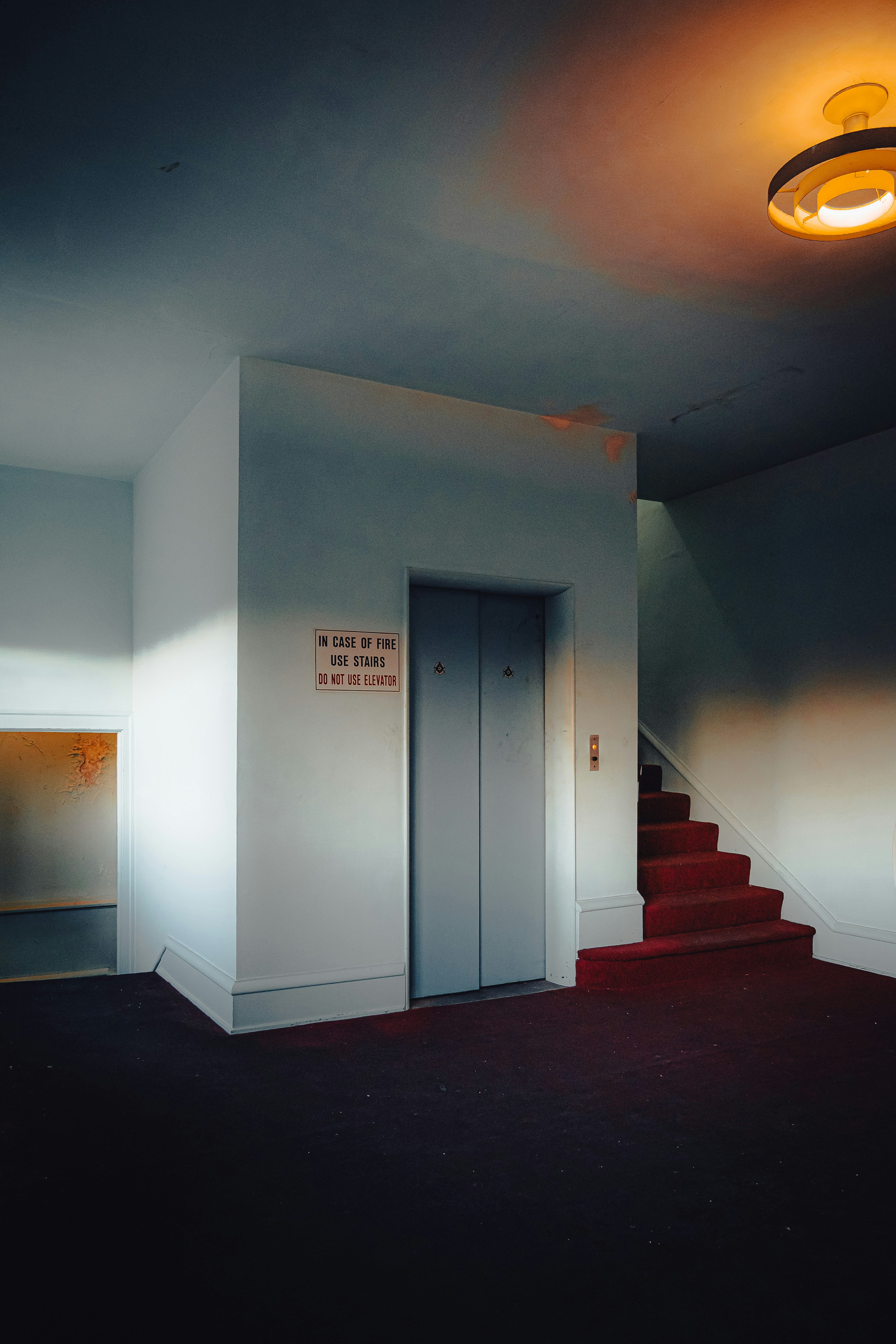 Elevator and red carpeted stairs in a hallway.