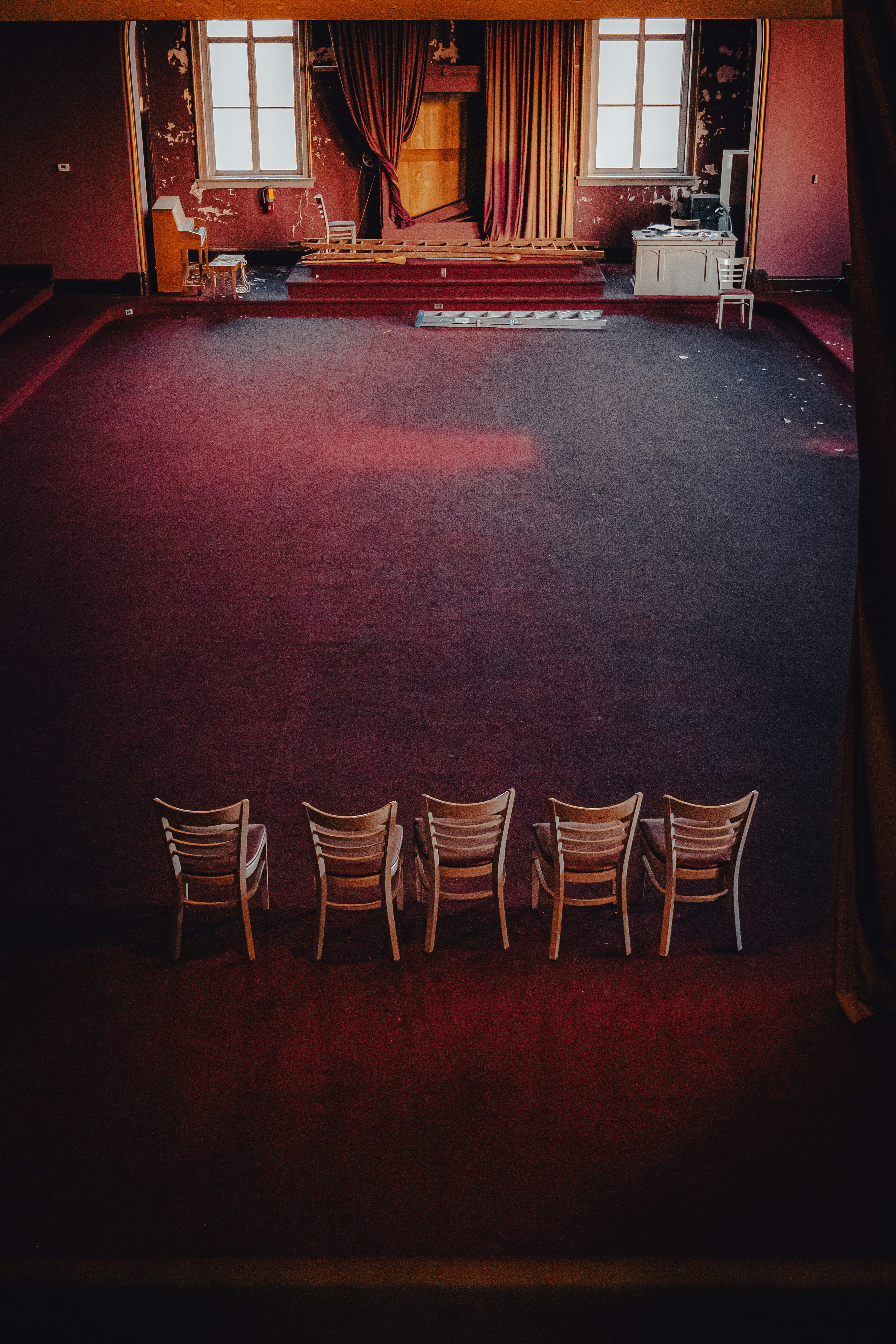 Five chairs face a dilapidated stage in an empty theater.