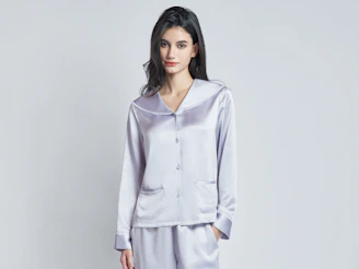 A woman wearing a light purple silk pajama set.