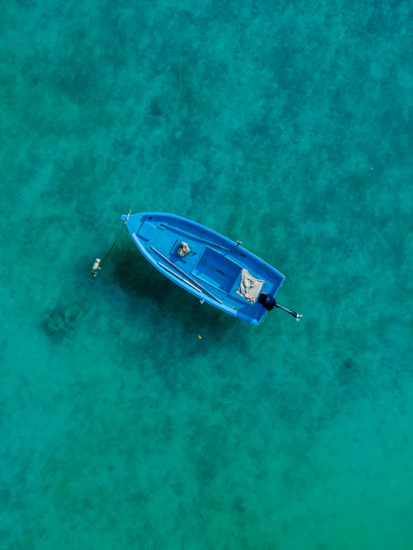 A single blue boat seen from above in clear Maldivian water