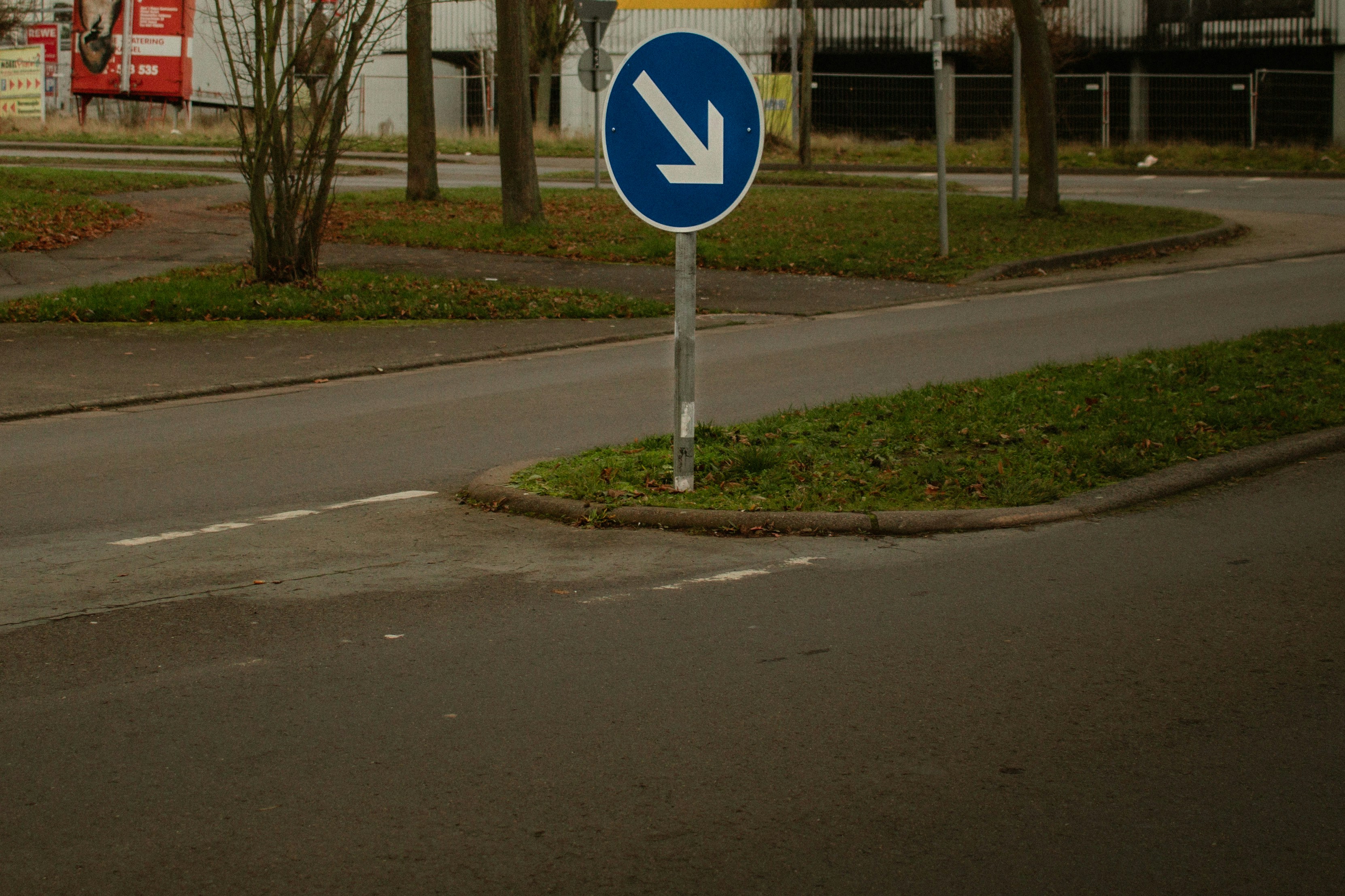 A blue traffic sign with a white arrow pointing down.