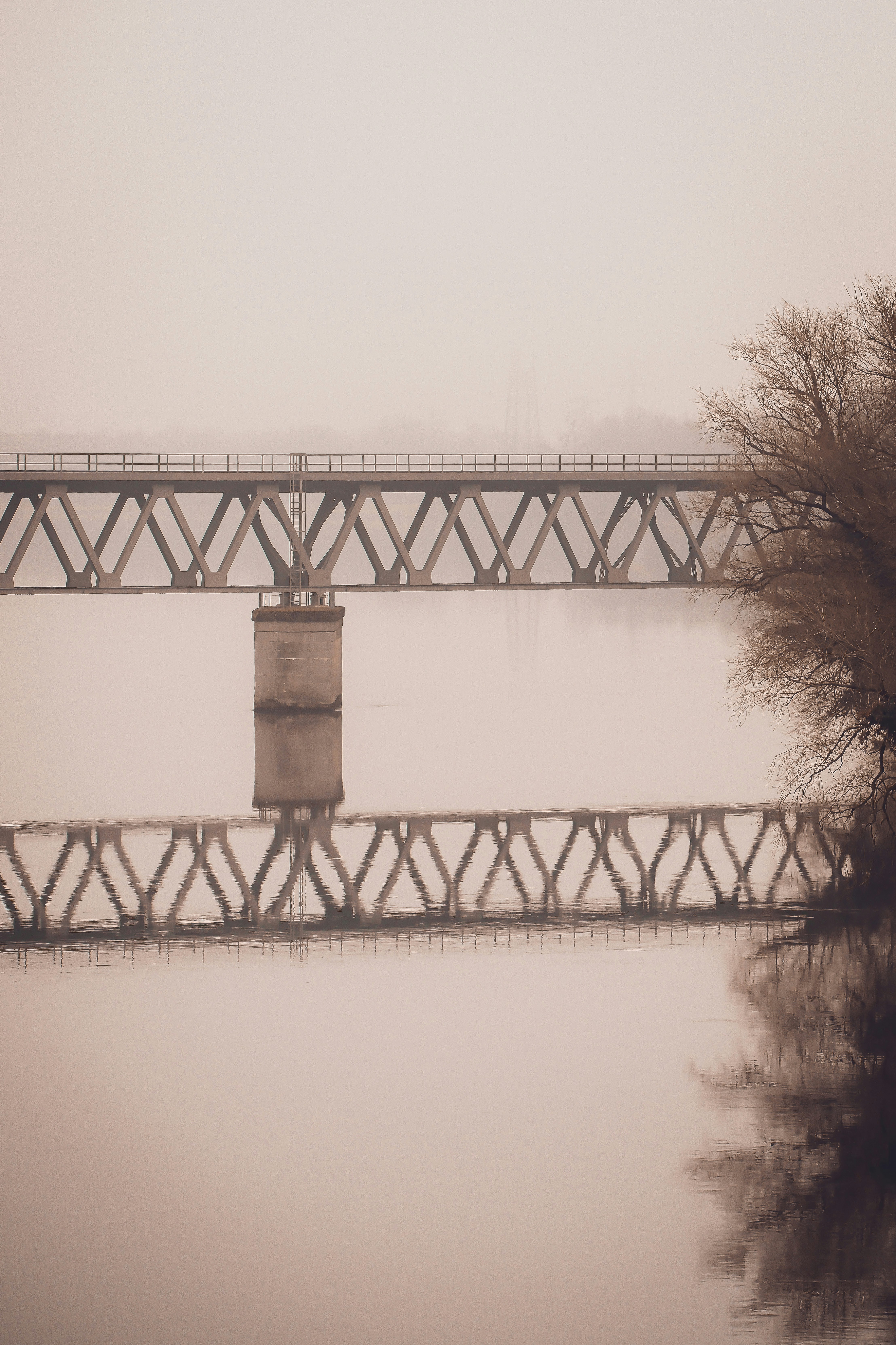 Un ponte su un fiume calmo in una giornata nebbiosa