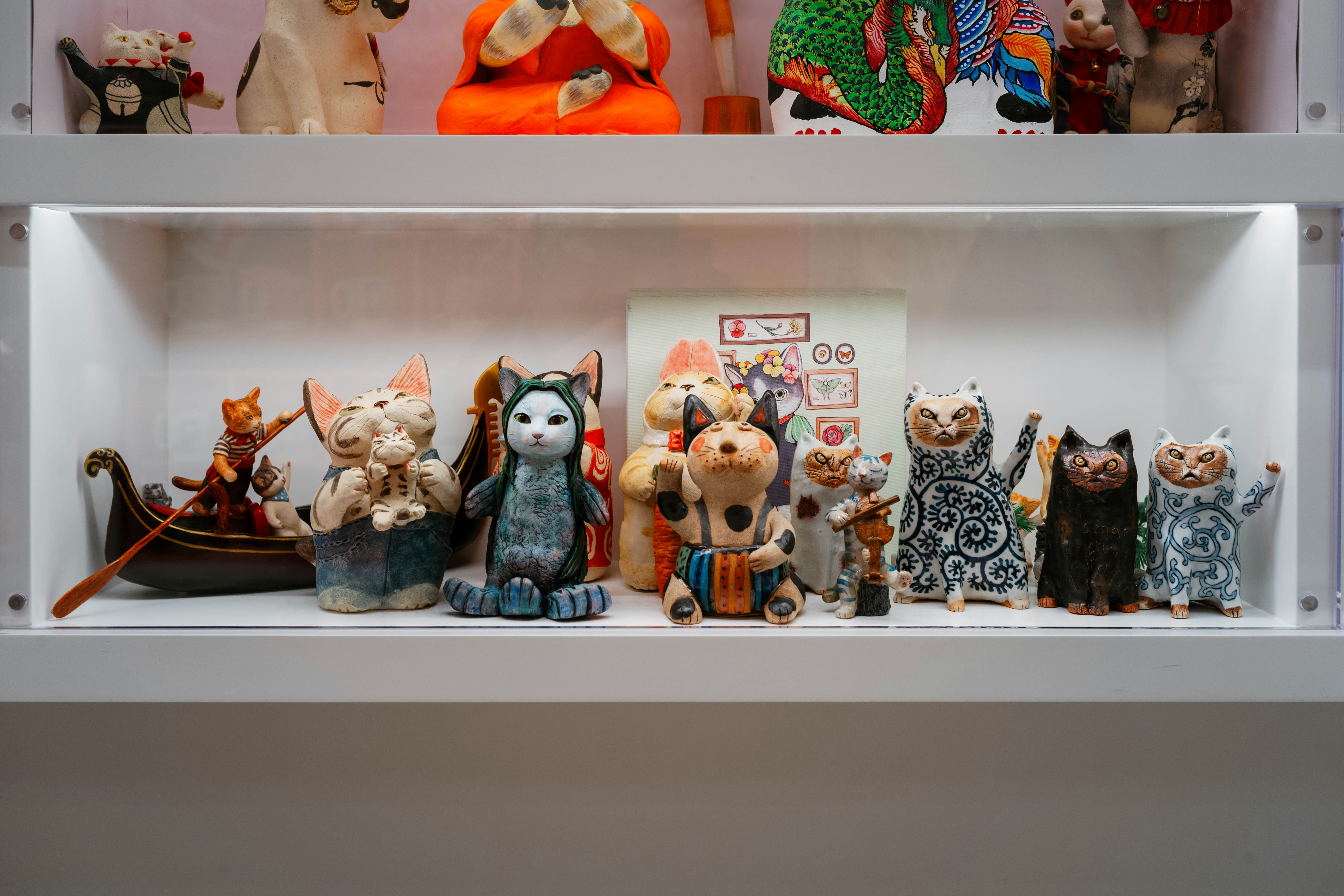 Collection of diverse cat figurines displayed on shelves.