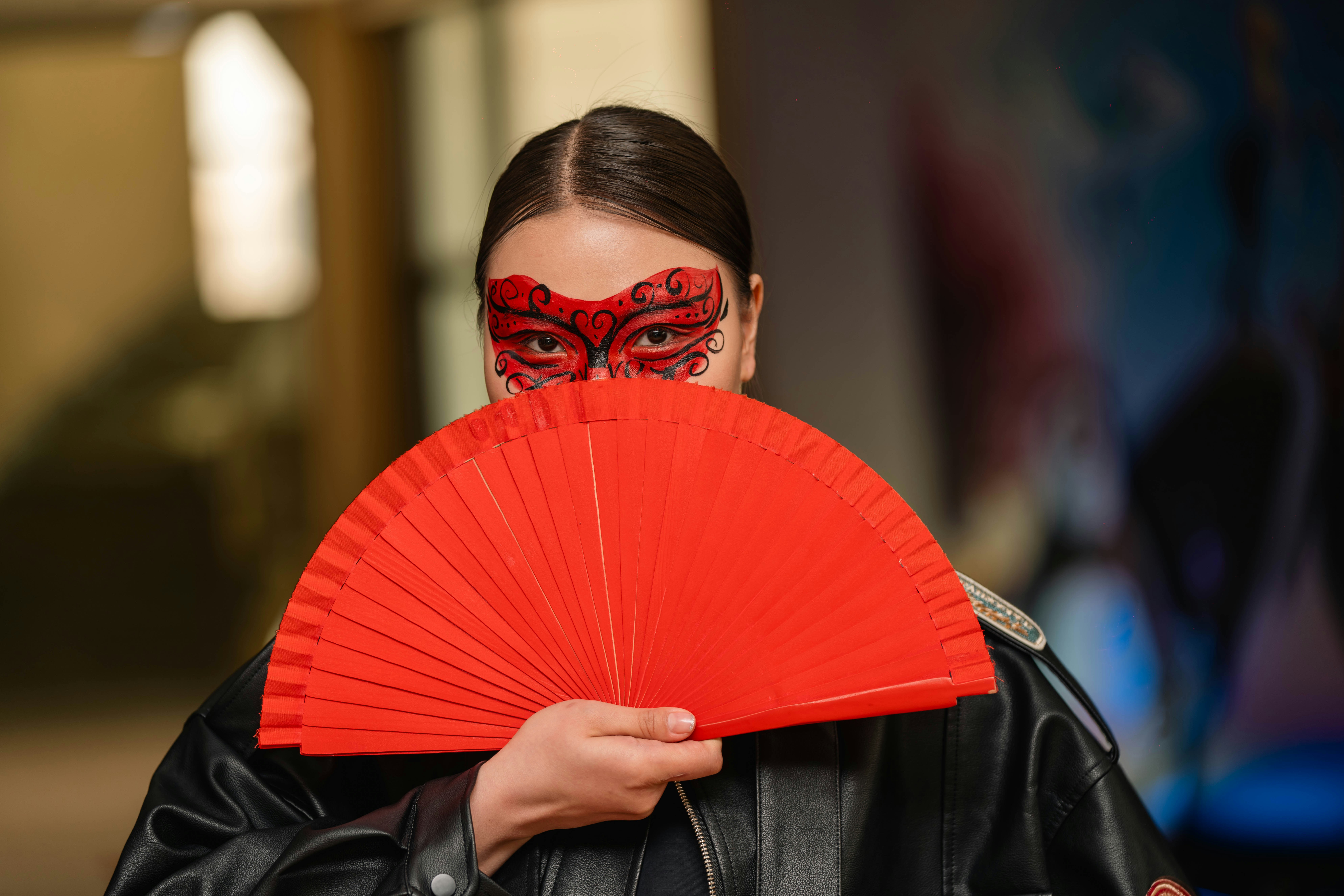 Woman in a red mask holding a red fan
