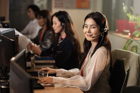 A smiling woman wearing a headset at a computer.