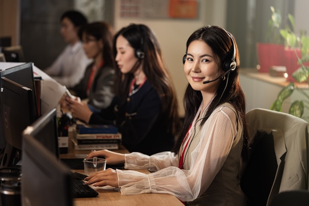 A smiling woman wearing a headset at a computer.