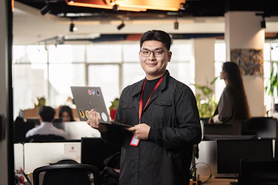 Man holding a laptop in a modern office setting.