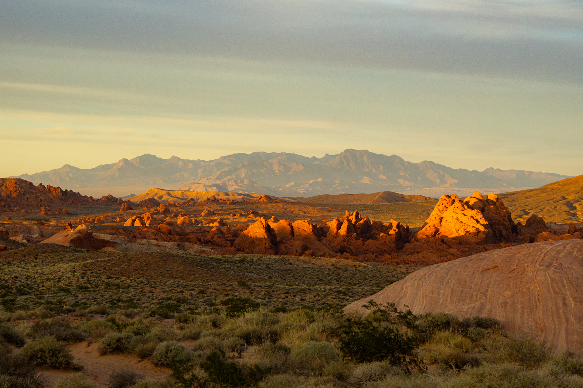 Golden sunset over rocky desert hills and distant mountains