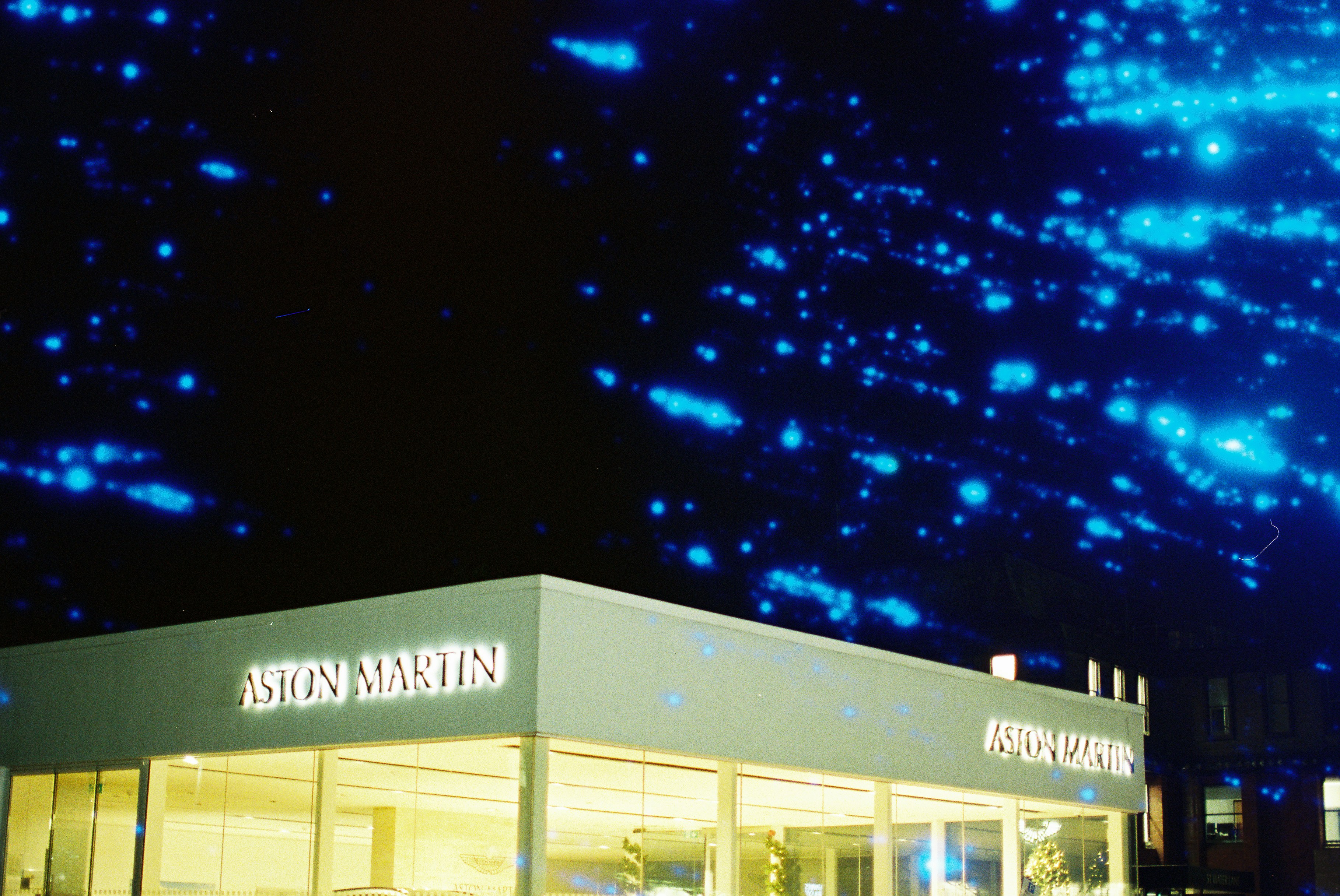 Aston martin dealership at night with blue lights