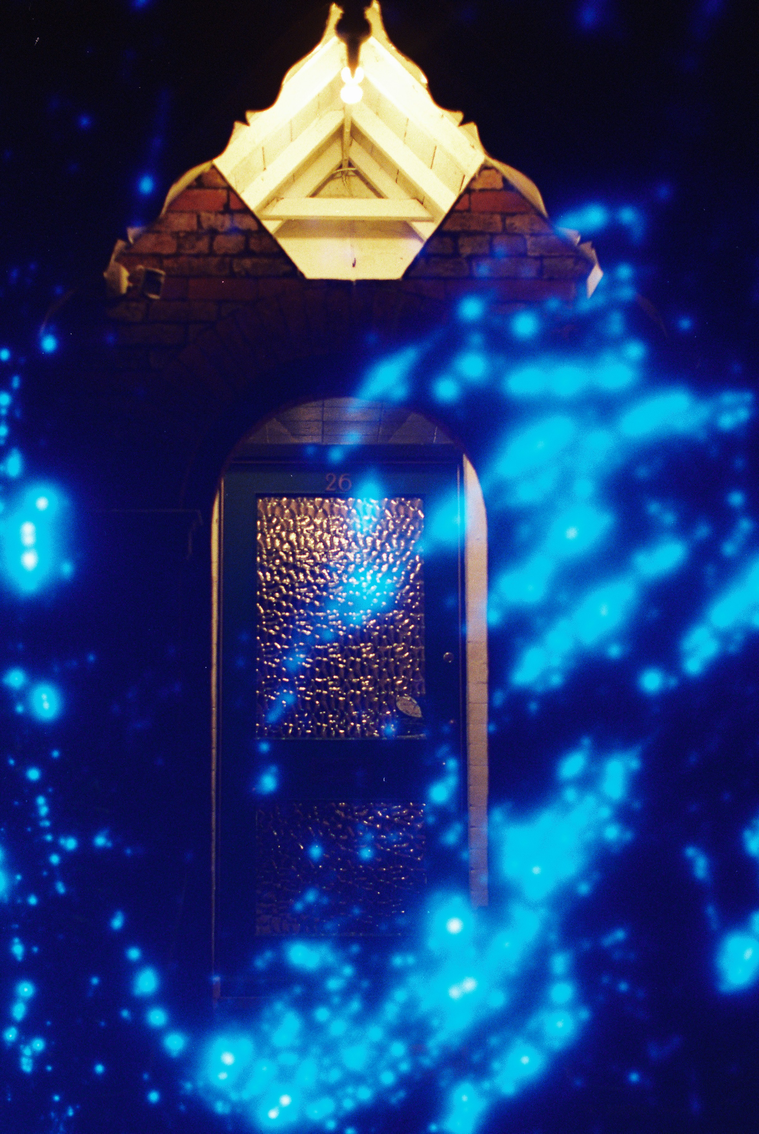 Leuchten von blauem Licht umgeben eine dunkle, gewölbte Tür.