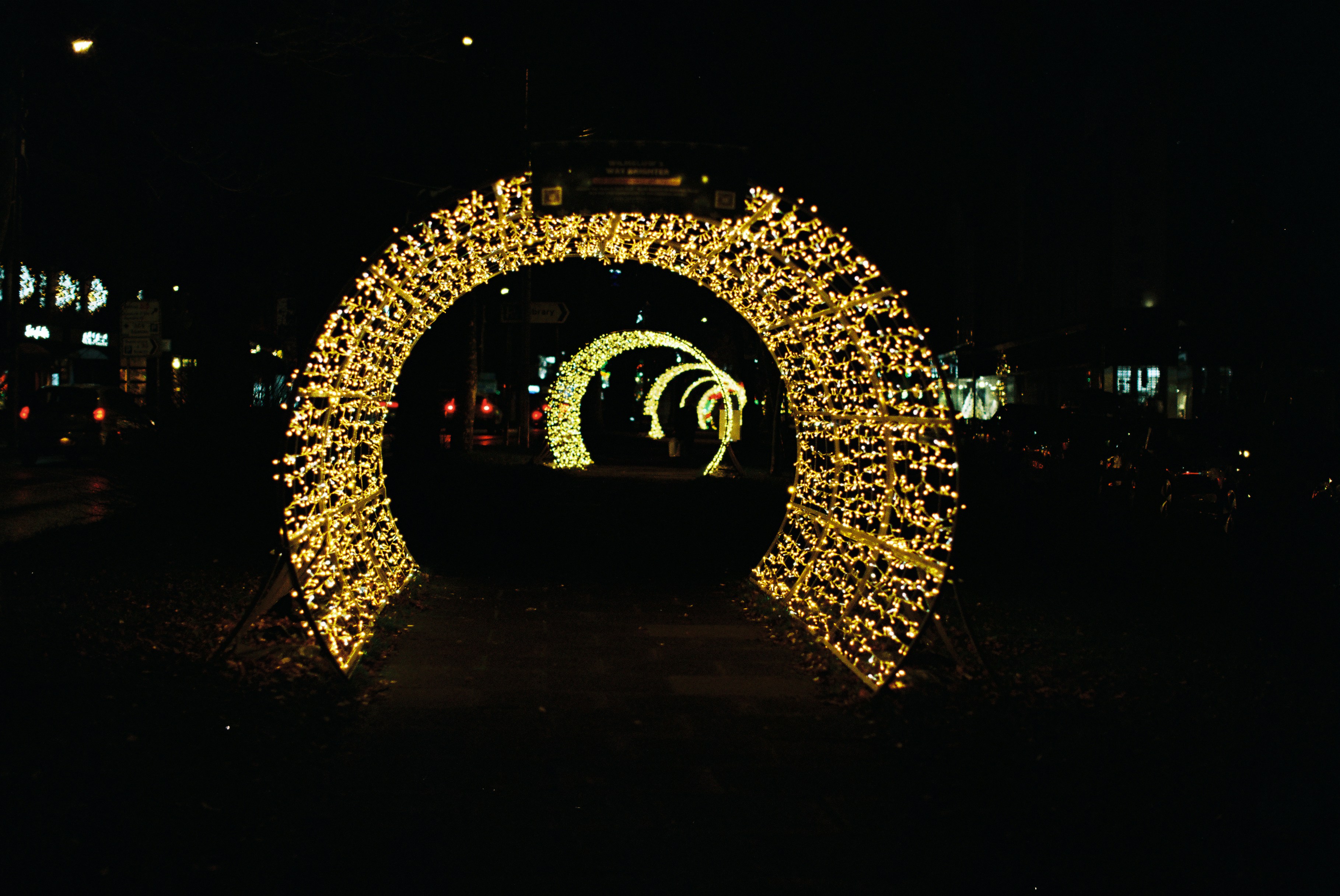 Illuminated archways light up a dark street at night.