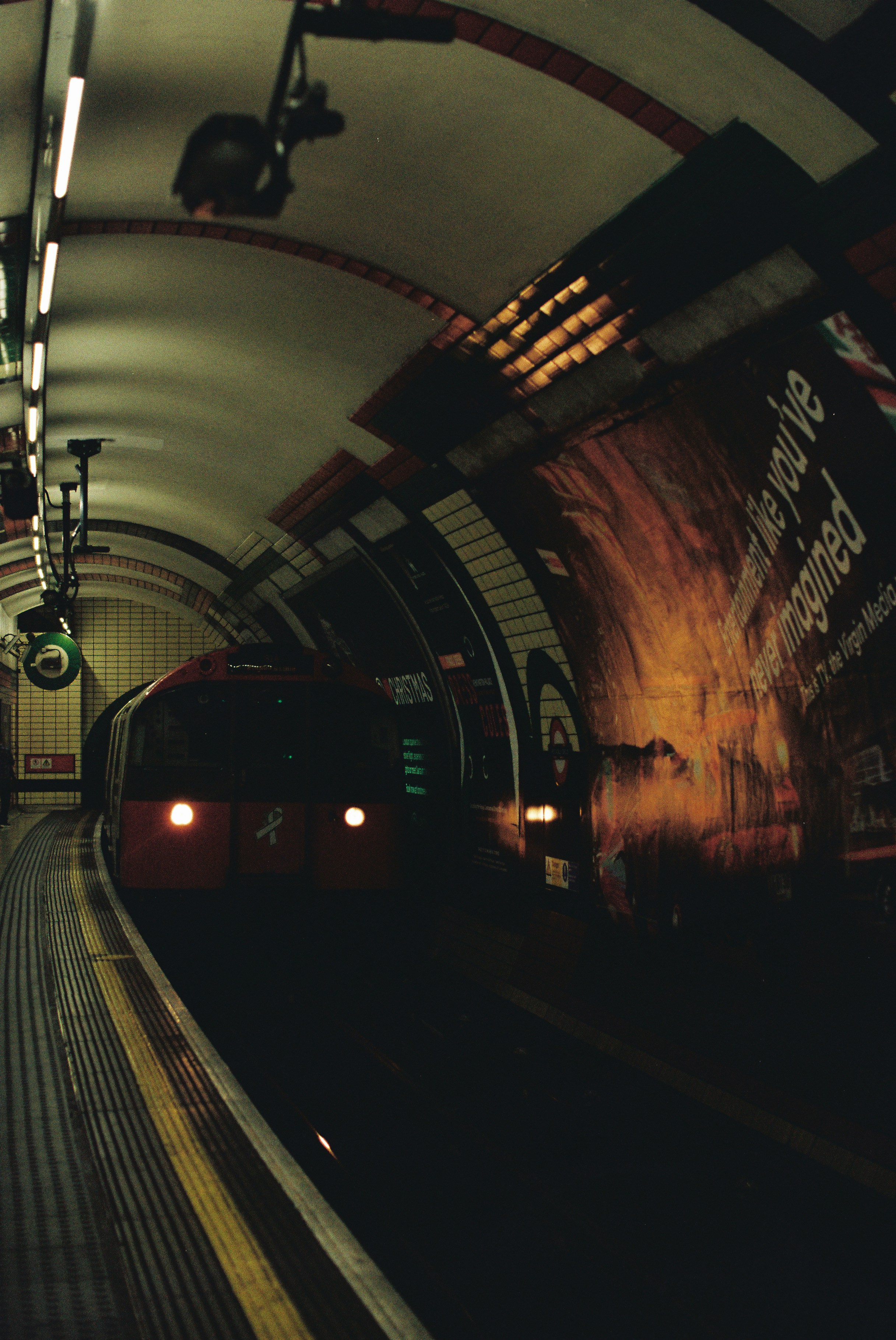 A red train arriving at a dark subway station.