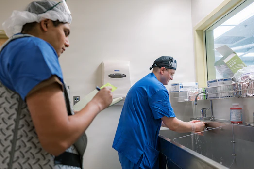 Two medical professionals washing hands at sink.
