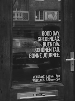 Door with greetings in multiple languages and business hours.