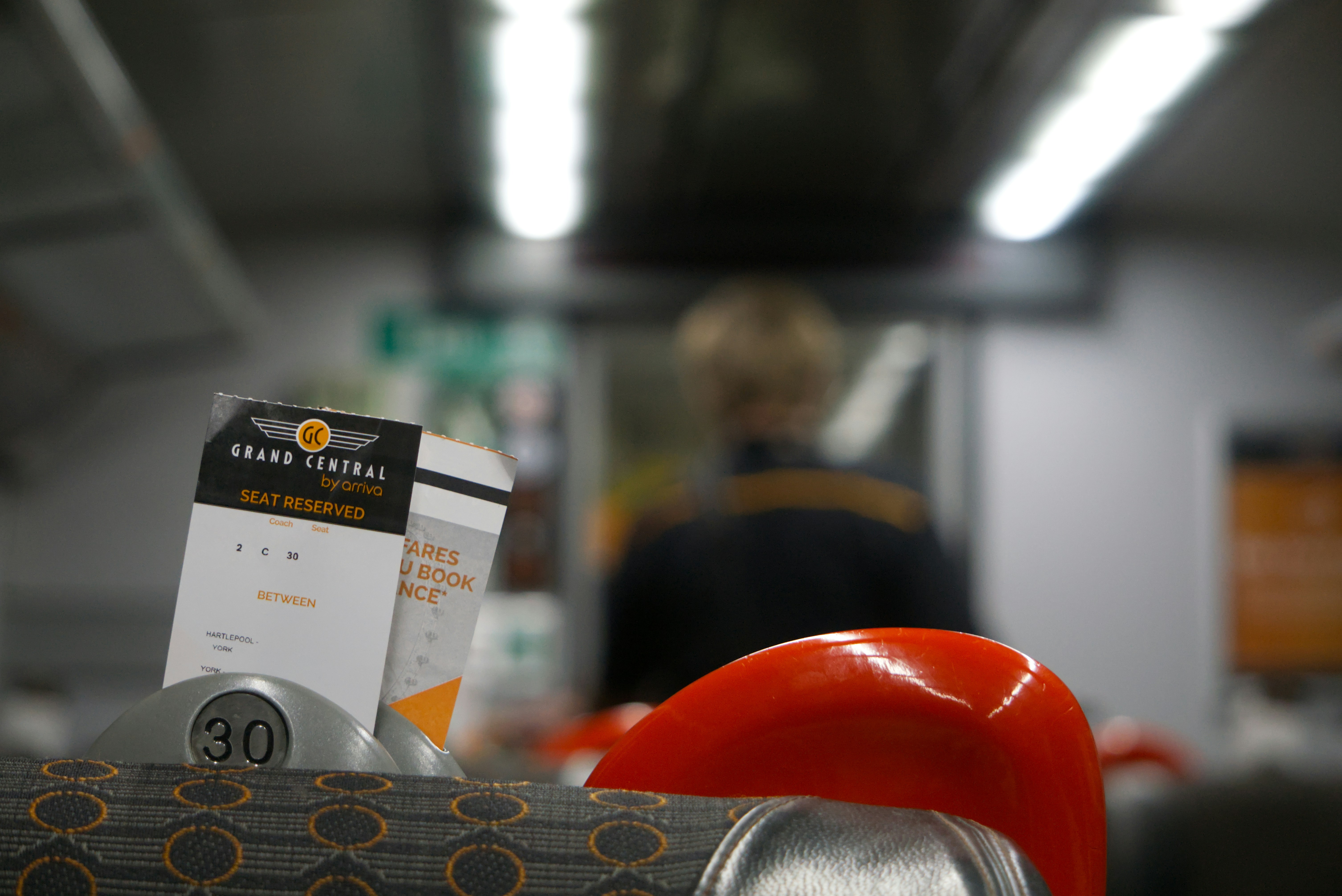 Two boxes on a train with person blurred in background.