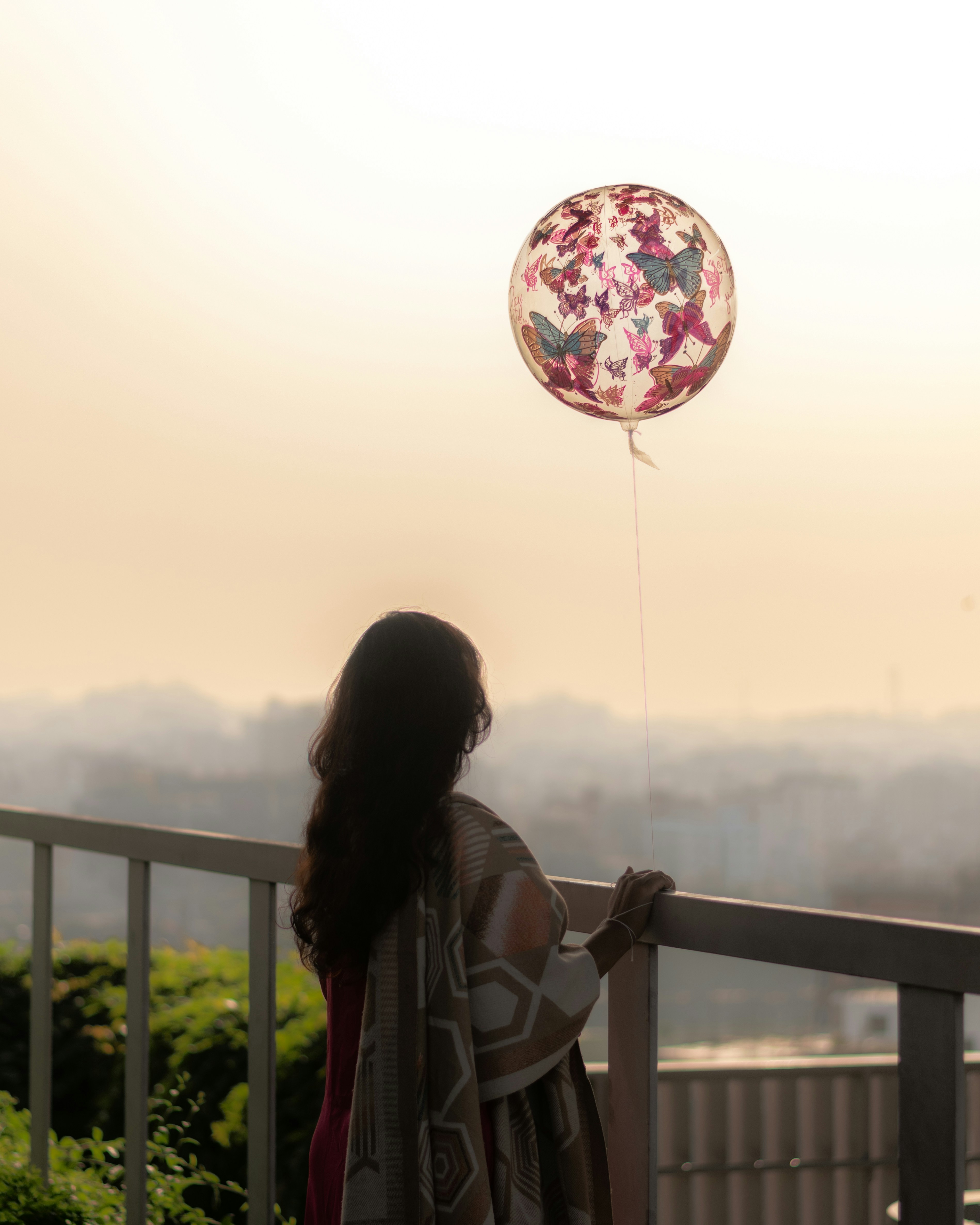 A woman holding a balloon, watching the sunset