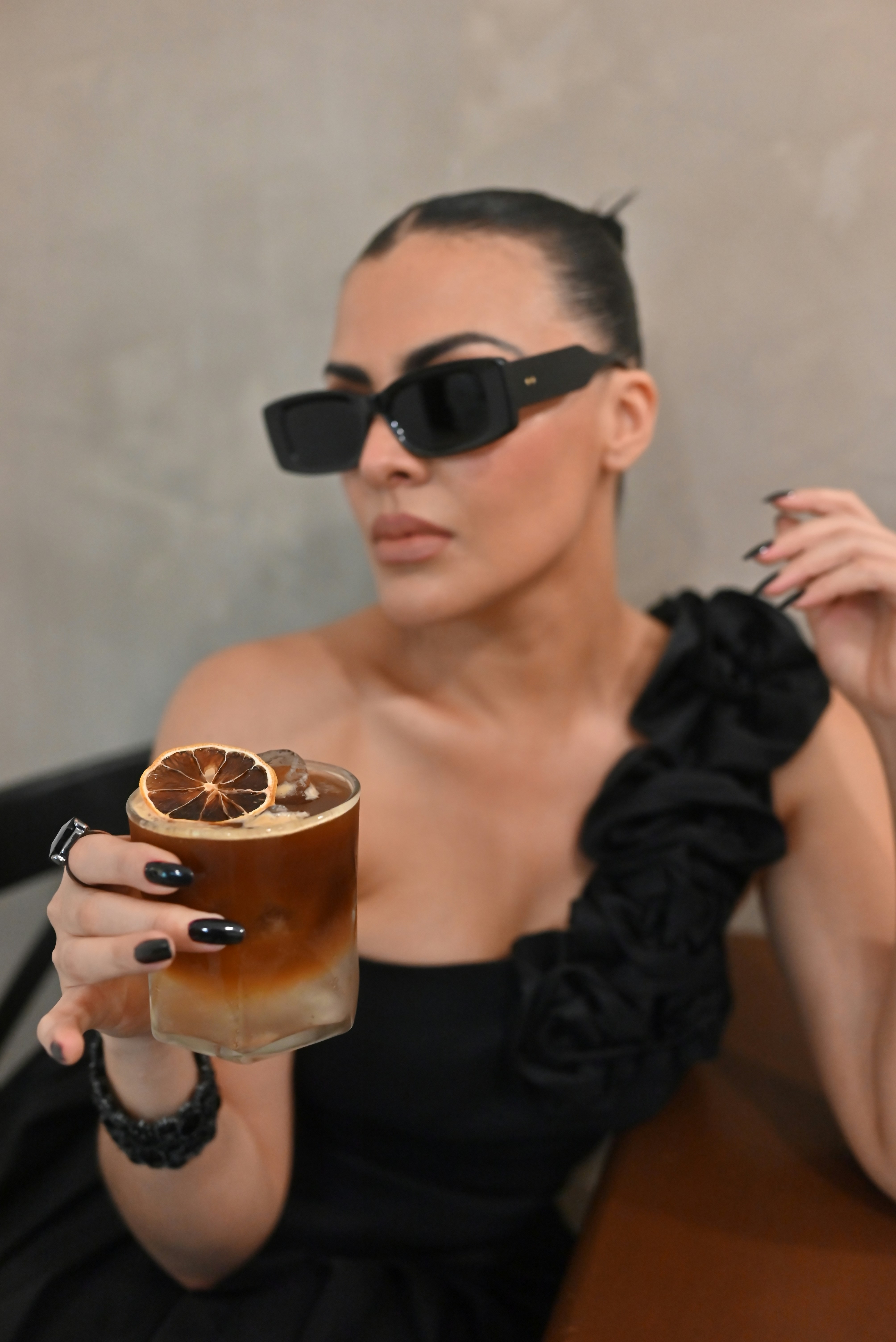 Woman in sunglasses holding a coffee with dried orange slice.