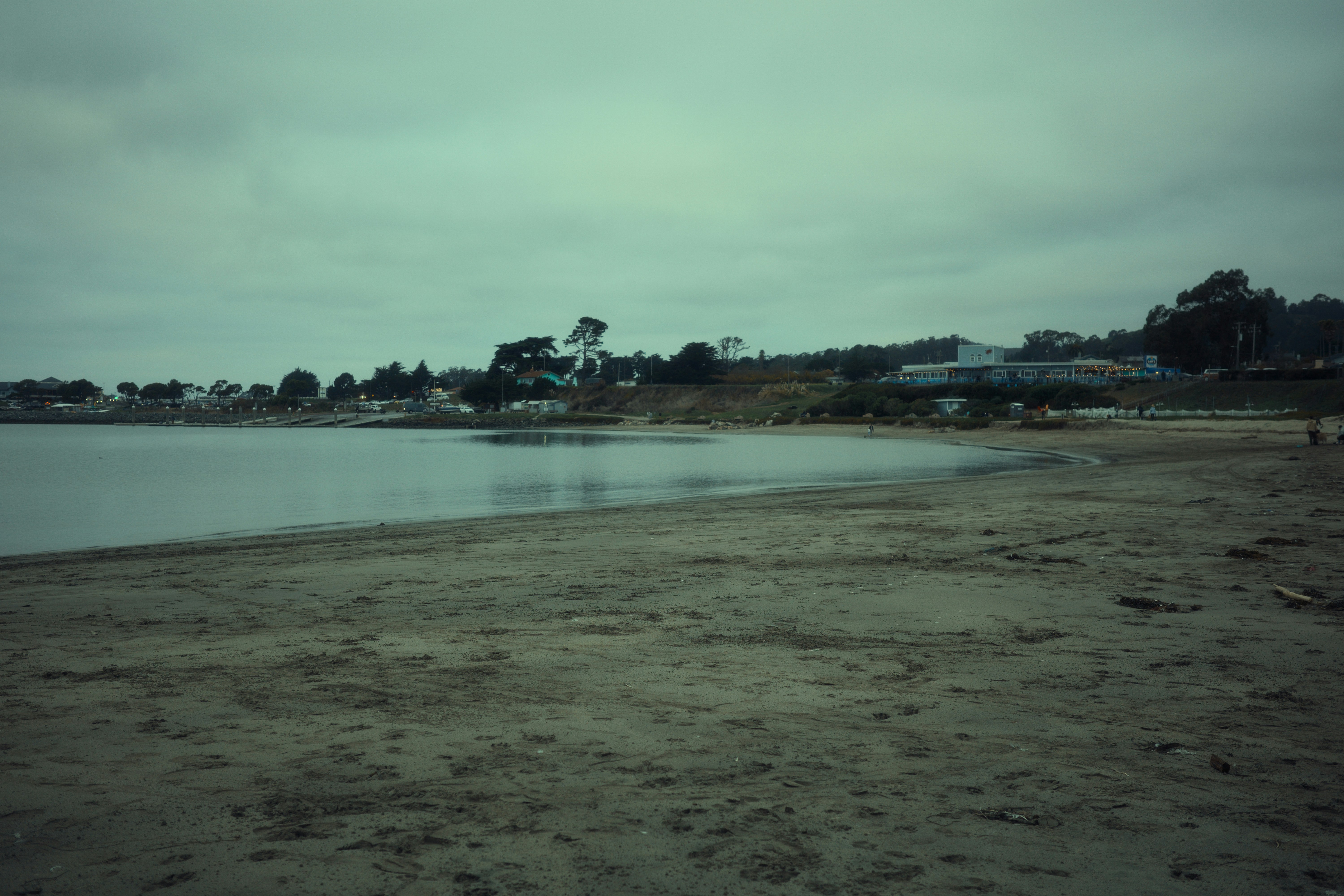 Sandy beach with calm water and distant buildings