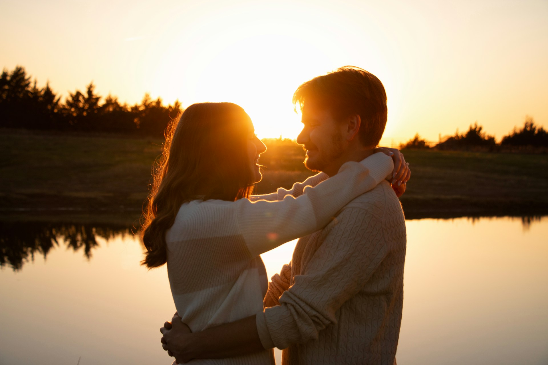 Couple embracing by a lake at sunset