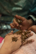 Henna artist applying intricate design to hand.