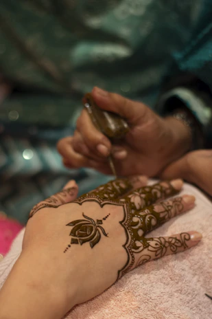 Henna artist applying intricate design to hand.