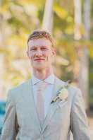 A smiling man in a light-colored suit and tie.