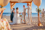 A wedding ceremony takes place on a sandy beach.