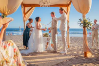 A wedding ceremony takes place on a sandy beach.