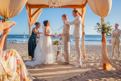 A wedding ceremony takes place on a sandy beach.