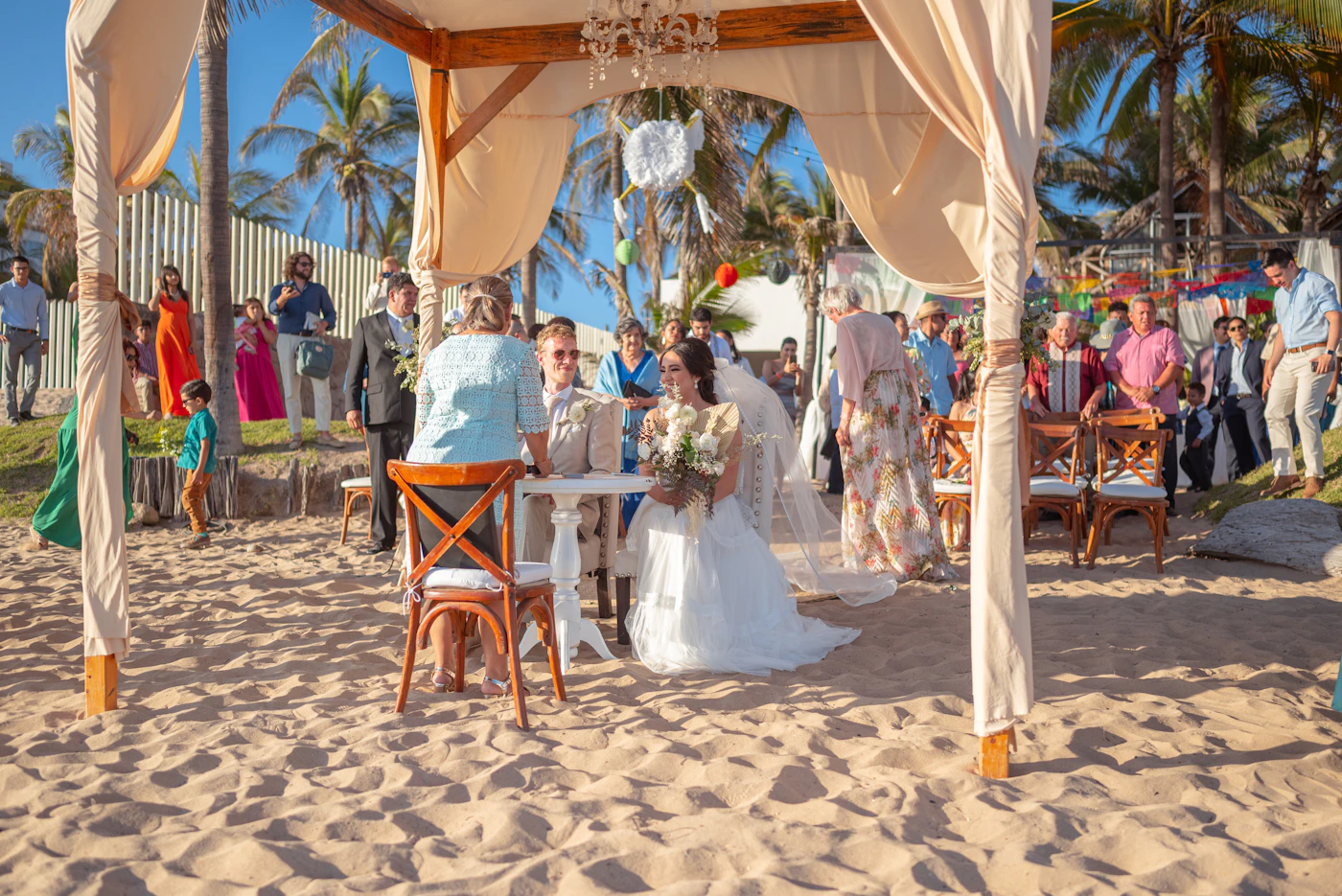 Bride and groom exchanging vows on a tropical sandy beach beneath palms