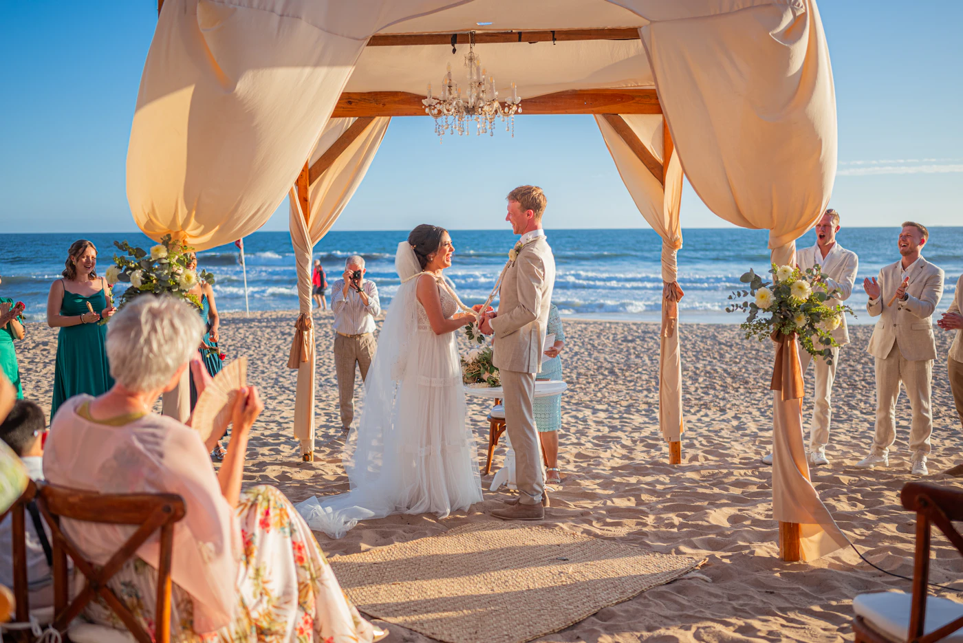 Waterproof wedding shoes for beach ceremonies — Bride walking barefoot on sandy beach in elegant waterproof shoes