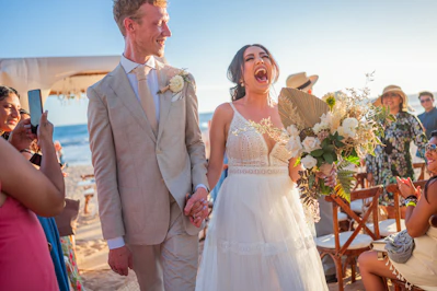 Newlyweds celebrating on a sunny beach wedding day.