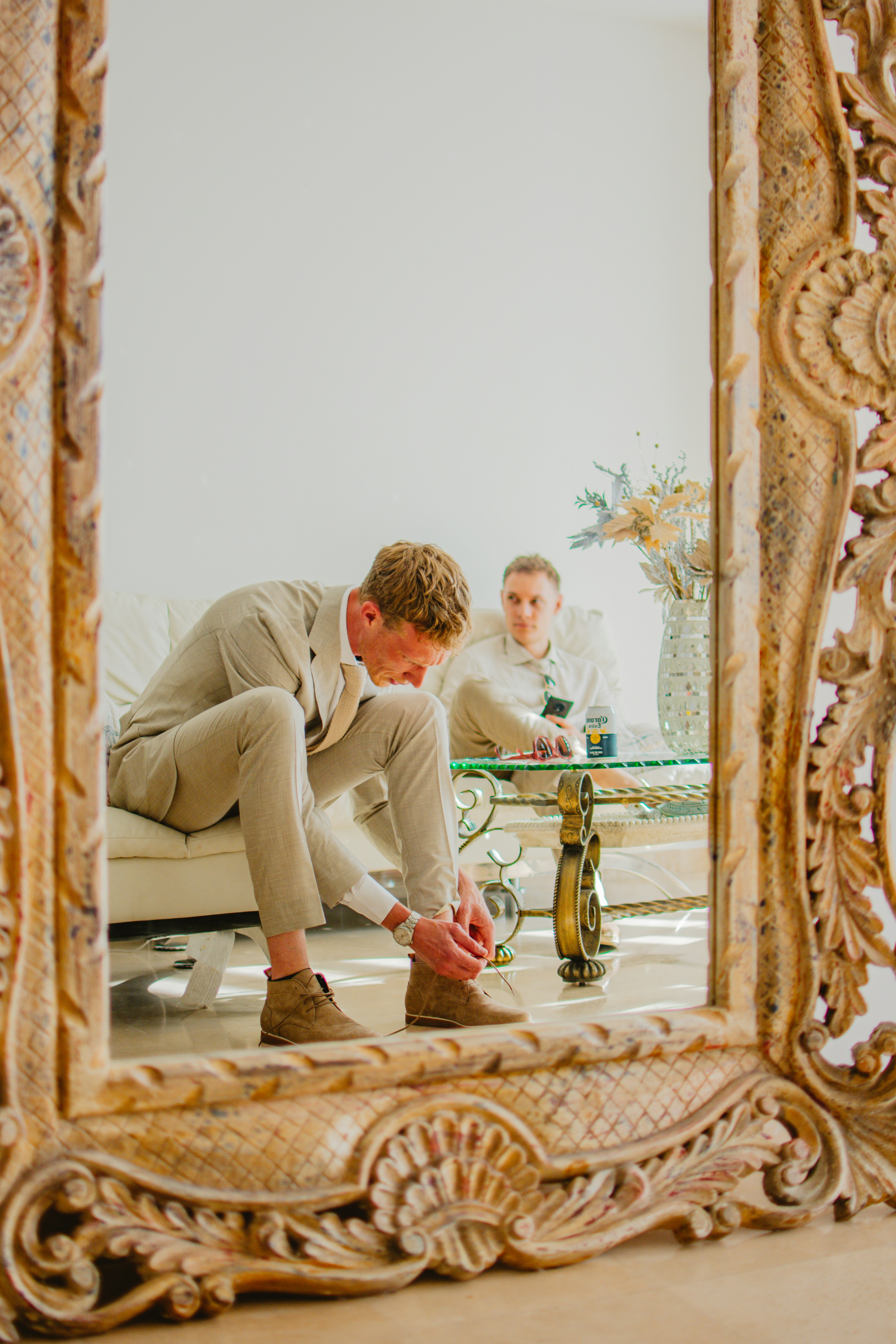 Man in suit tying shoes, reflection in mirror