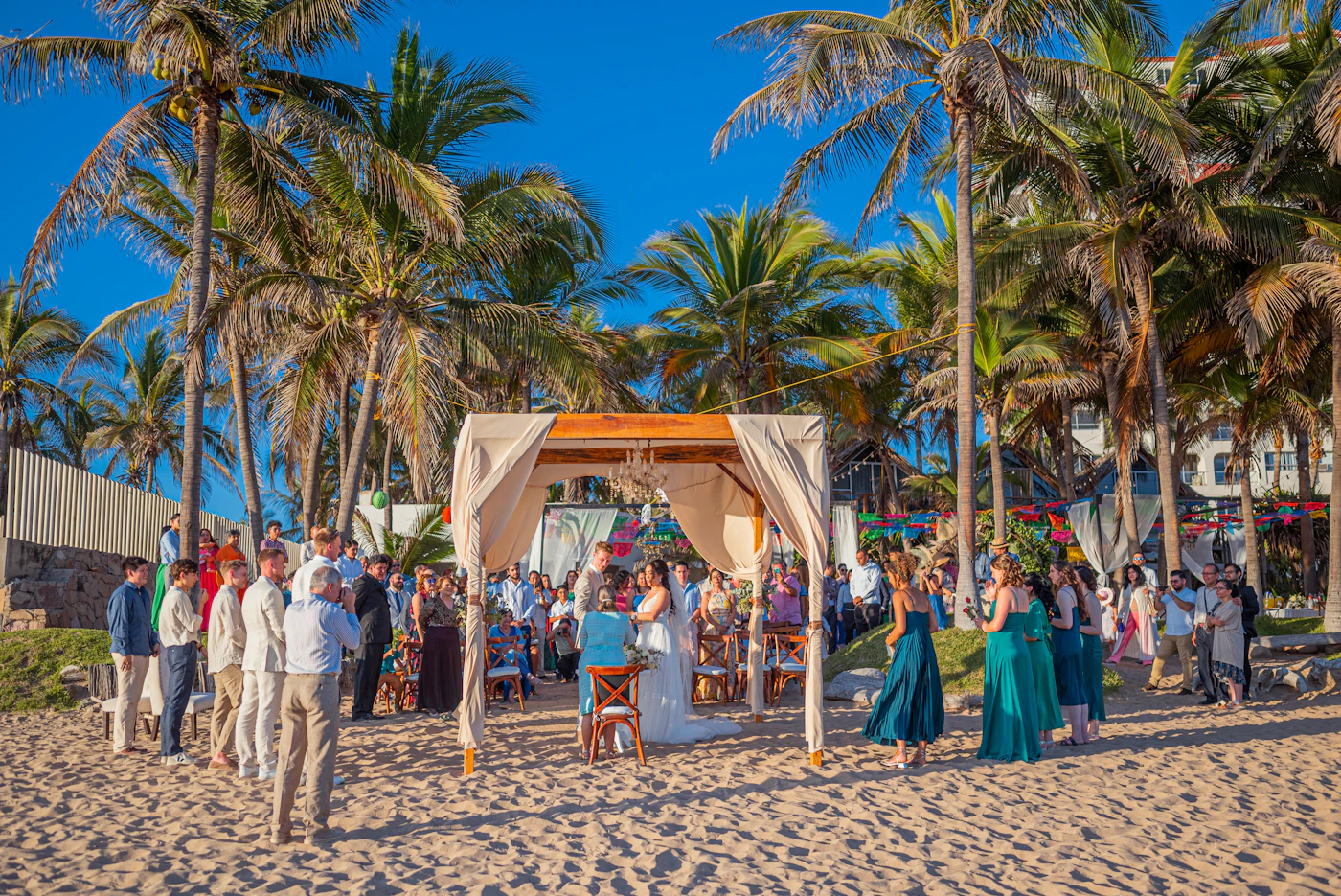 Newlywed couple exchanging vows on a sandy shore lined with palms