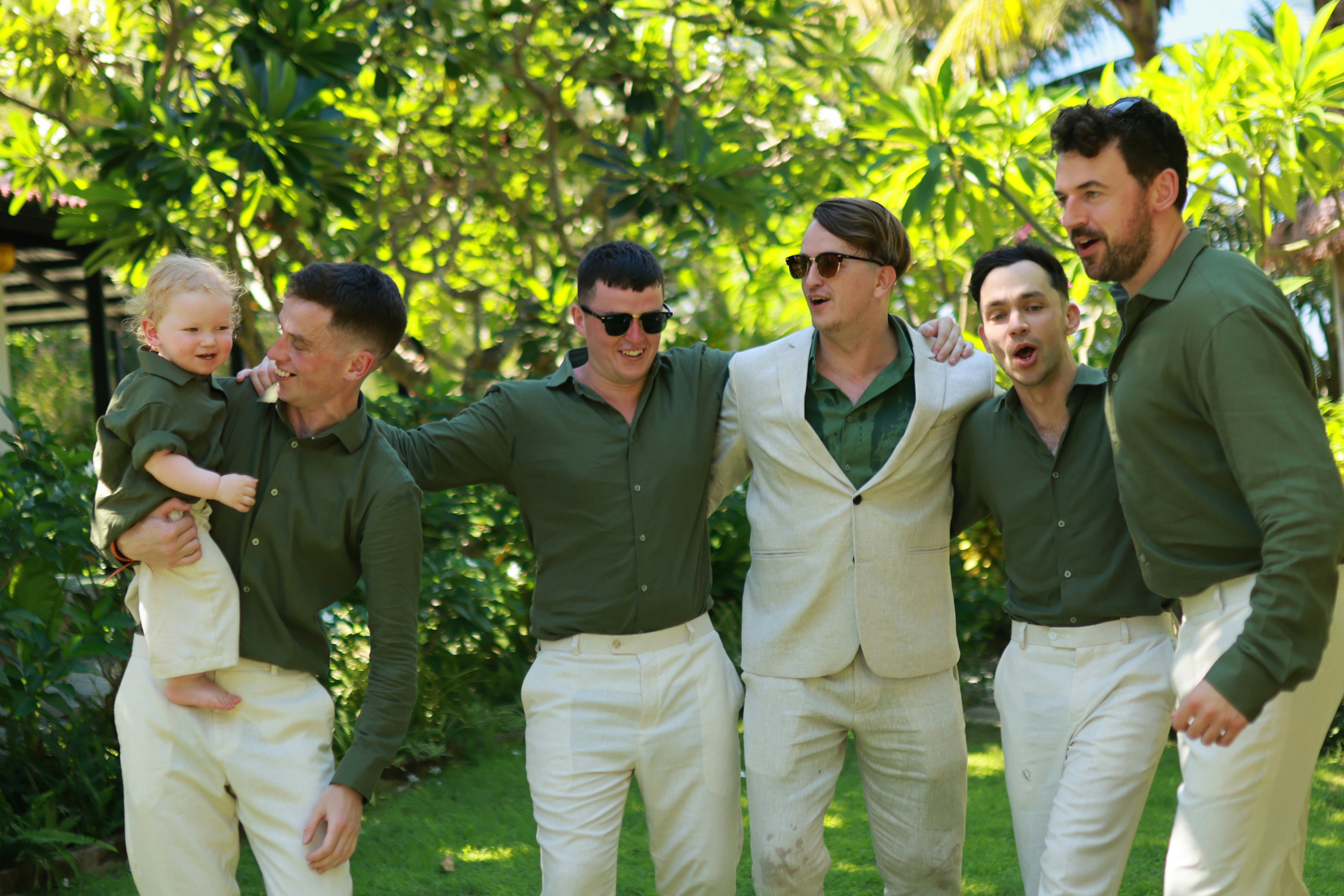 Groom and groomsmen with baby outdoors