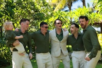 Groom and groomsmen celebrating outdoors with a child.
