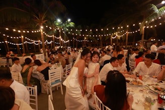 Wedding reception with guests dining outdoors at tables under lights