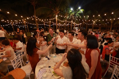 People celebrating at an outdoor night event with string lights.