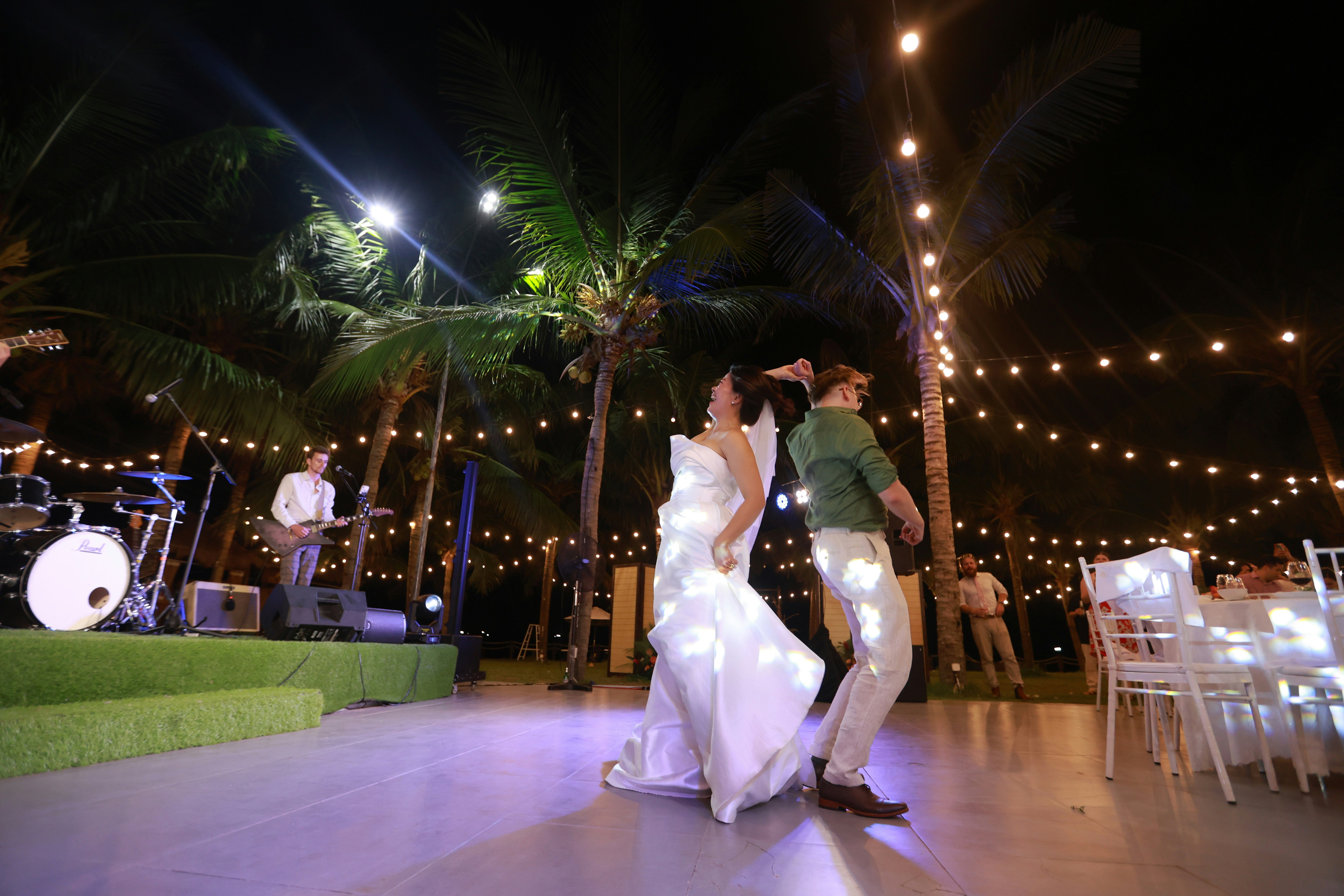 Couple dancing at a wedding reception outdoors at night.
