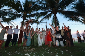 Wedding party celebrating under palm trees at dusk.