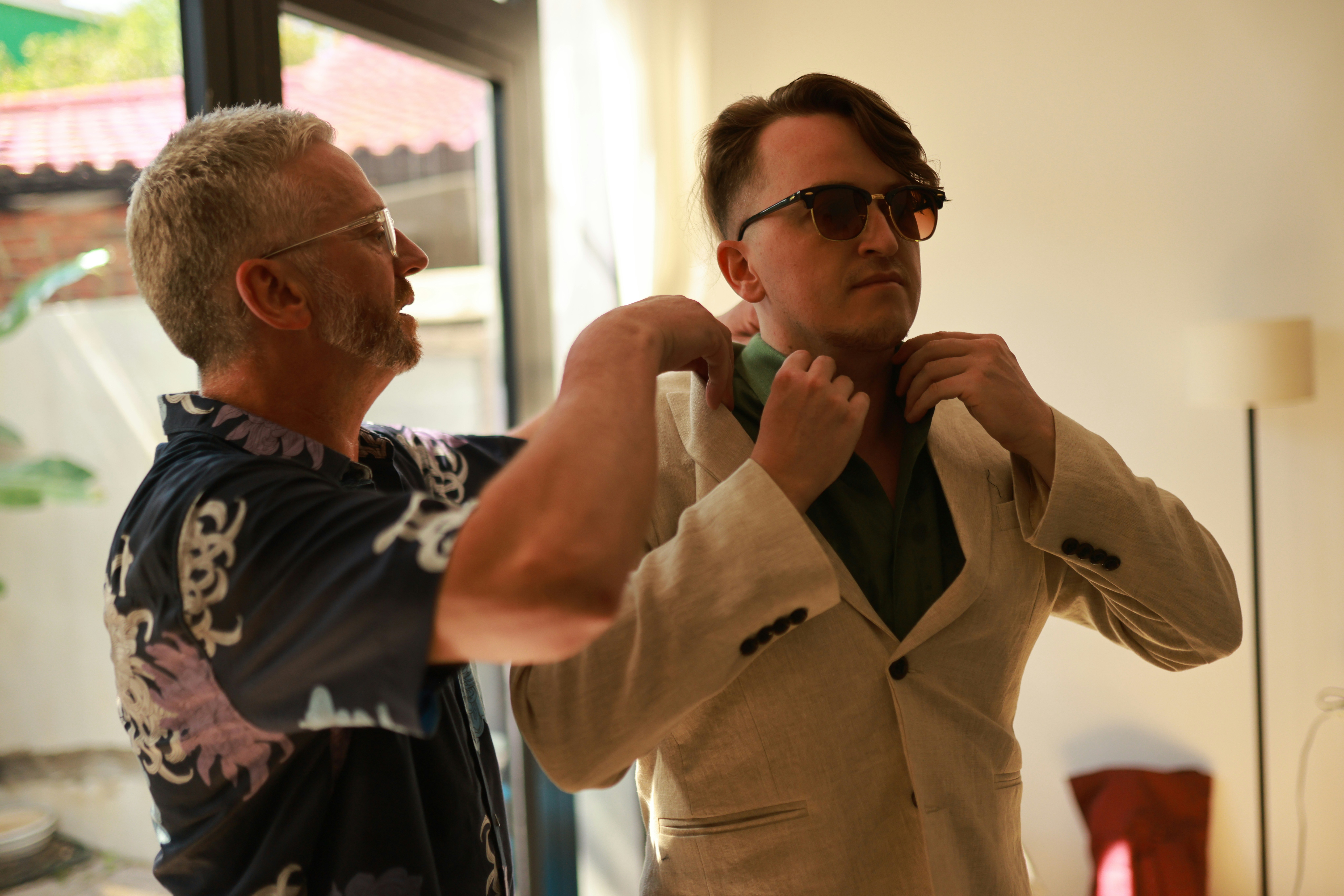 Man helps another man adjust his suit jacket