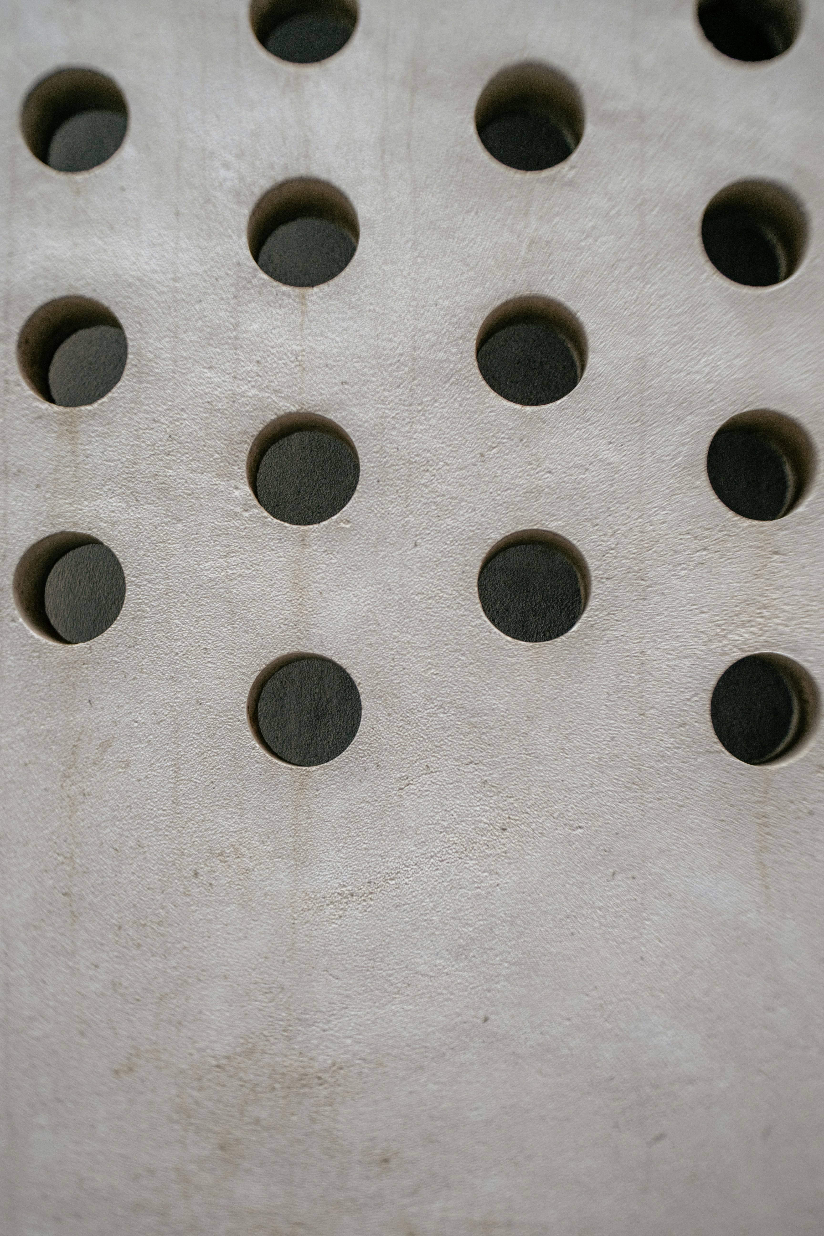 A pattern of circular holes in a light gray surface.