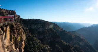 A small building perched on a cliff overlooking a canyon.