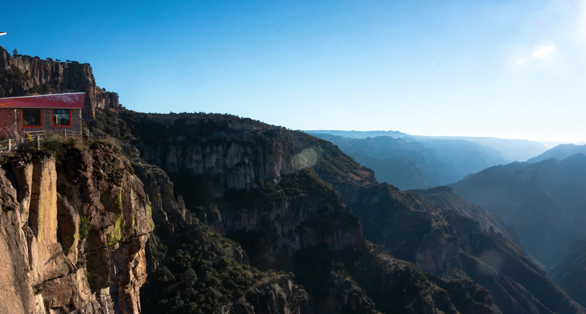 A small building perched on a cliff overlooking a canyon.