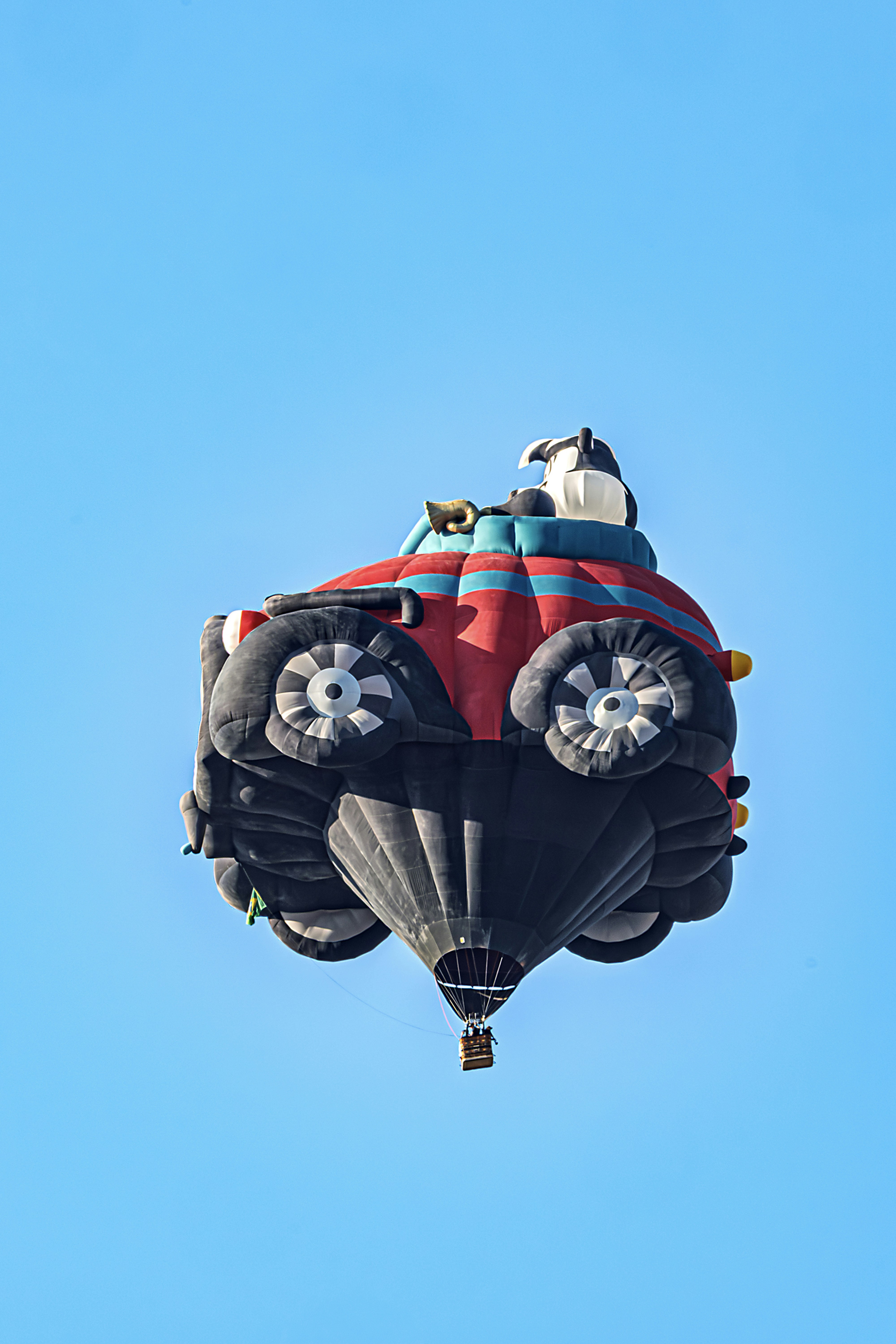A hot air balloon shaped like a car flying.
