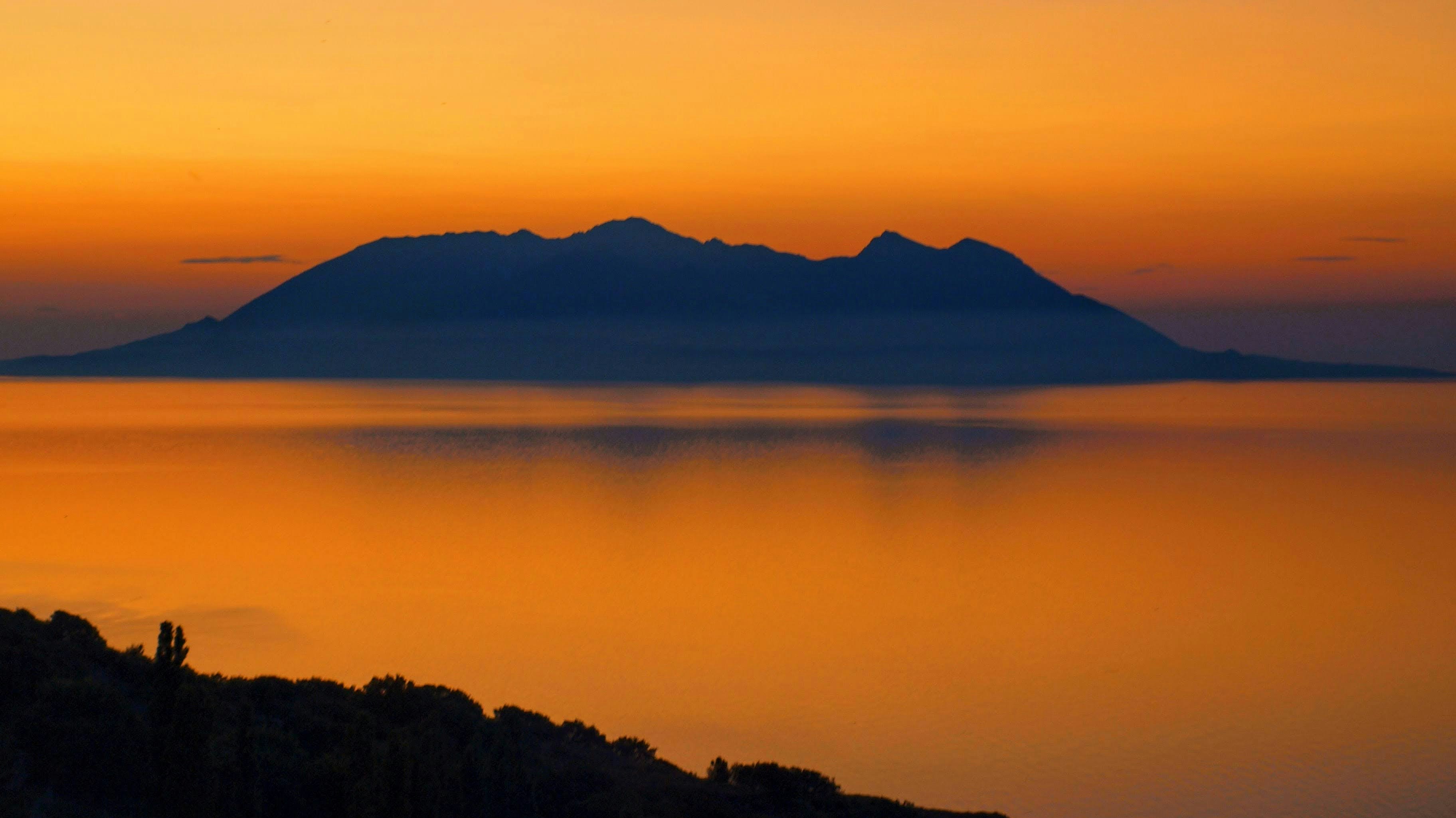 Silhouette of an island against a vibrant orange sunset